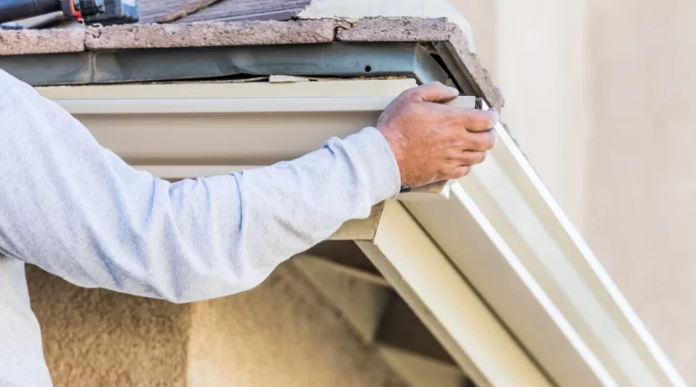 person holding up gutter as they fix it